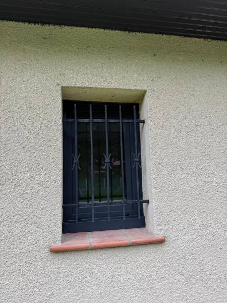 Pose de fenêtre à un seul vantail en aluminium noir sécurisée par grille de défense à Colomiers